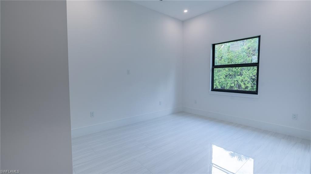 Room featuring light-toned flooring, white walls, and a black-framed window