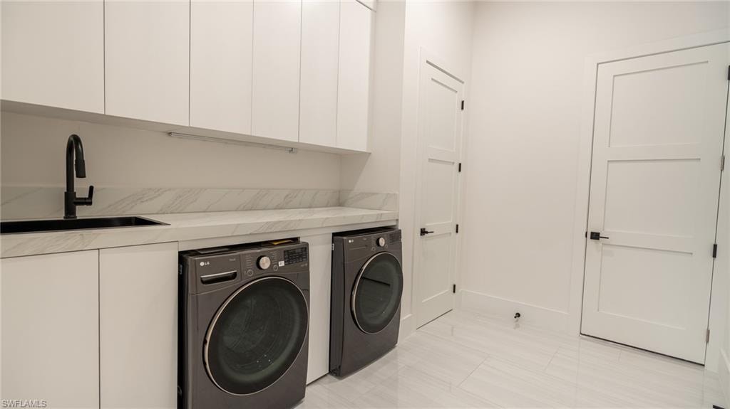 Laundry area featuring a large sink with a matte black faucet, white cabinetry, light-toned countertop, and two panel doors