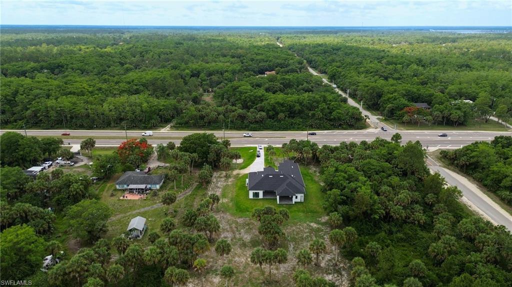 Expansive parcel featuring a modern single-story residence with a dark shingled roof, surrounded by mature trees and native vegetation
