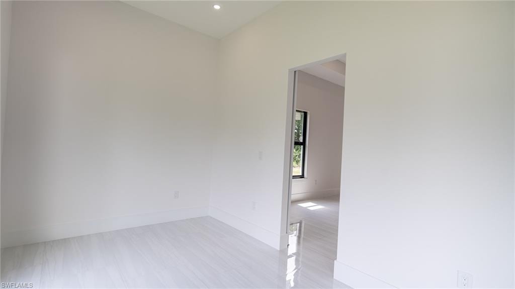 Spacious room featuring white tile flooring, recessed lighting, and a wide entryway
