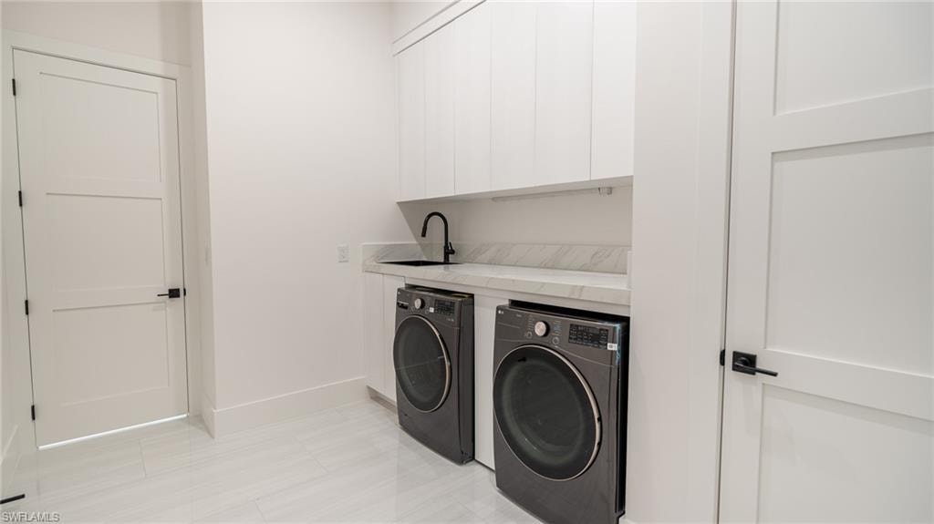Contemporary laundry room featuring white cabinetry, light-toned countertop, and a matte black faucet over a black sink