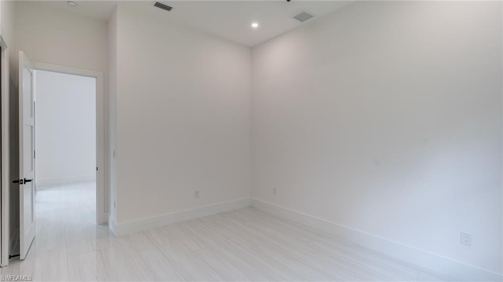 Bright room featuring light-toned flooring, white walls, and recessed lighting