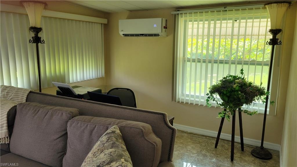Behind couch of living room with desk and mini split.