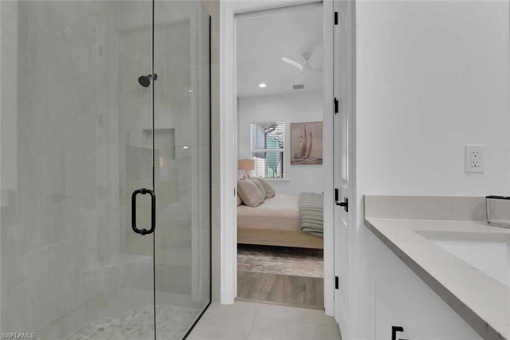 Bathroom featuring ensuite bathroom, a shower stall, visible vents, a sink, and tile patterned floors