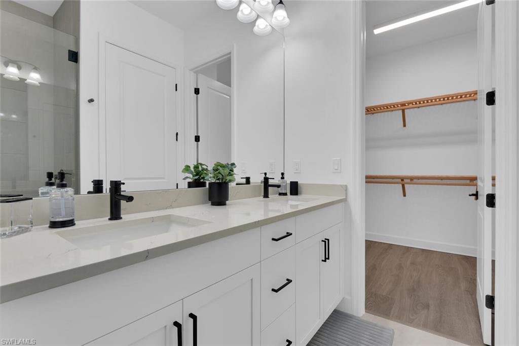 Full bathroom featuring a sink, a walk in closet, and wood finished floors