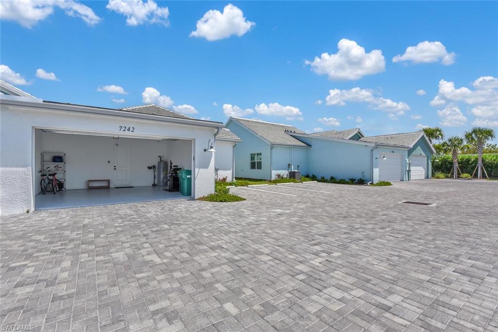 Rear view of property featuring a garage, stucco siding, a tiled roof, and decorative driveway