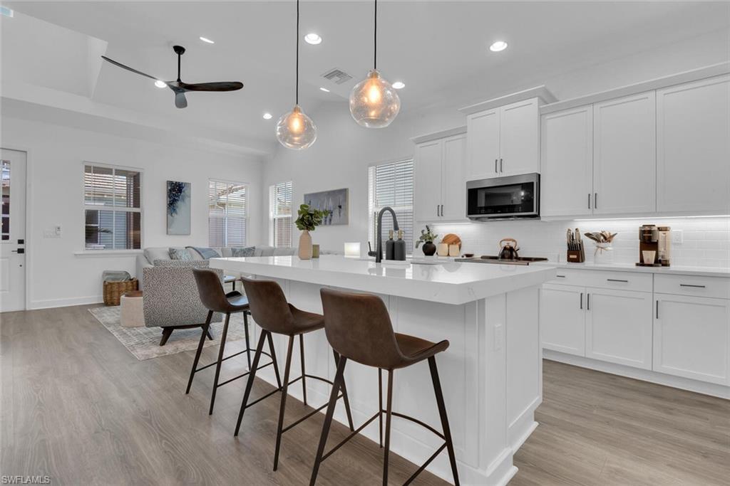 Kitchen featuring stainless steel microwave, open floor plan, ceiling fan, and decorative backsplash