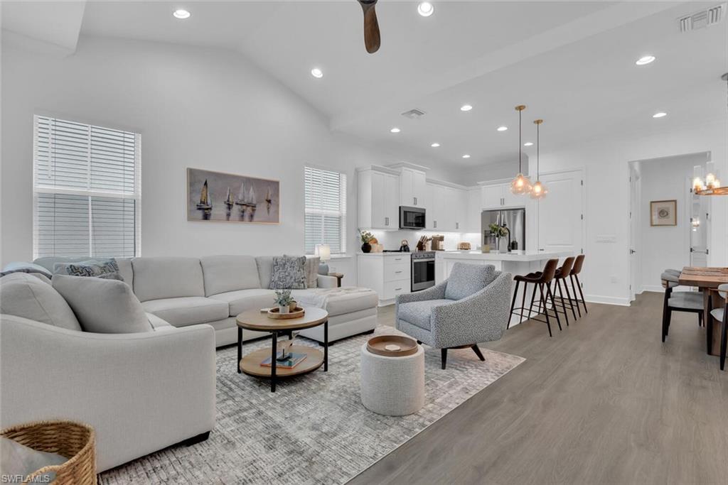 Living area featuring visible vents, baseboards, recessed lighting, ceiling fan with notable chandelier, and light wood-style flooring