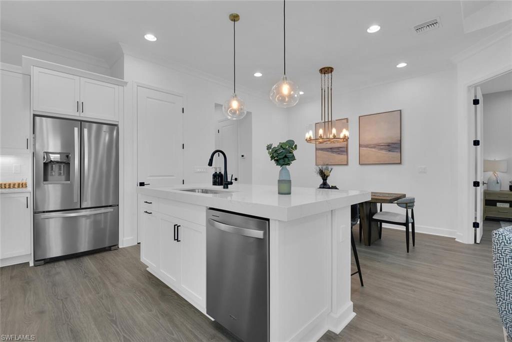 Kitchen featuring ornamental molding, visible vents, wood finished floors, a sink, and stainless steel appliances