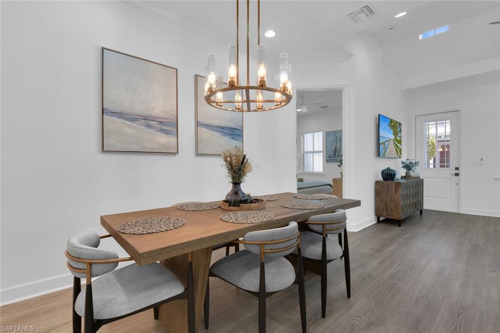 Dining area with a wealth of natural light, visible vents, an inviting chandelier, and wood finished floors