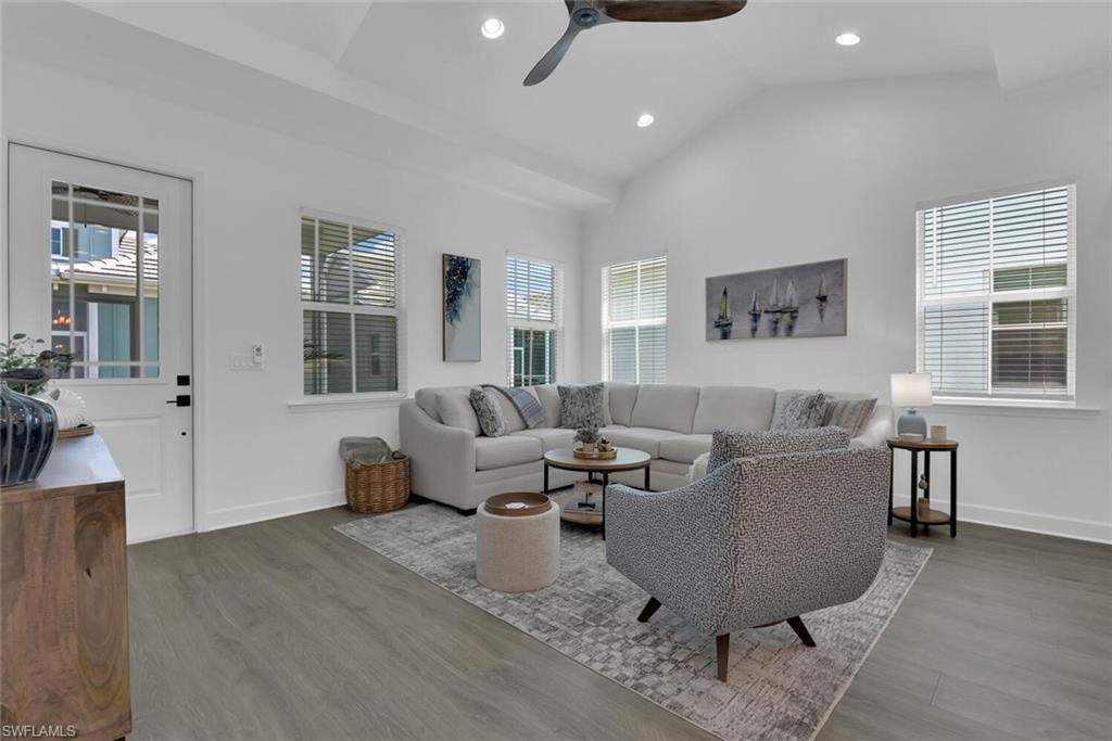 Living area with lofted ceiling, baseboards, and wood finished floors