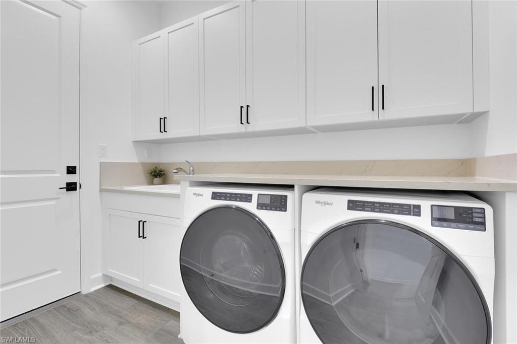 Washroom with cabinet space, light wood finished floors, separate washer and dryer, and a sink