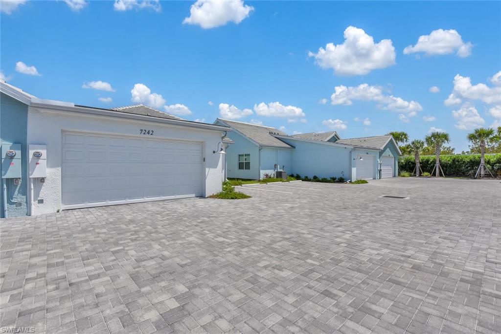 Ranch-style home with an attached garage, stucco siding, and decorative driveway