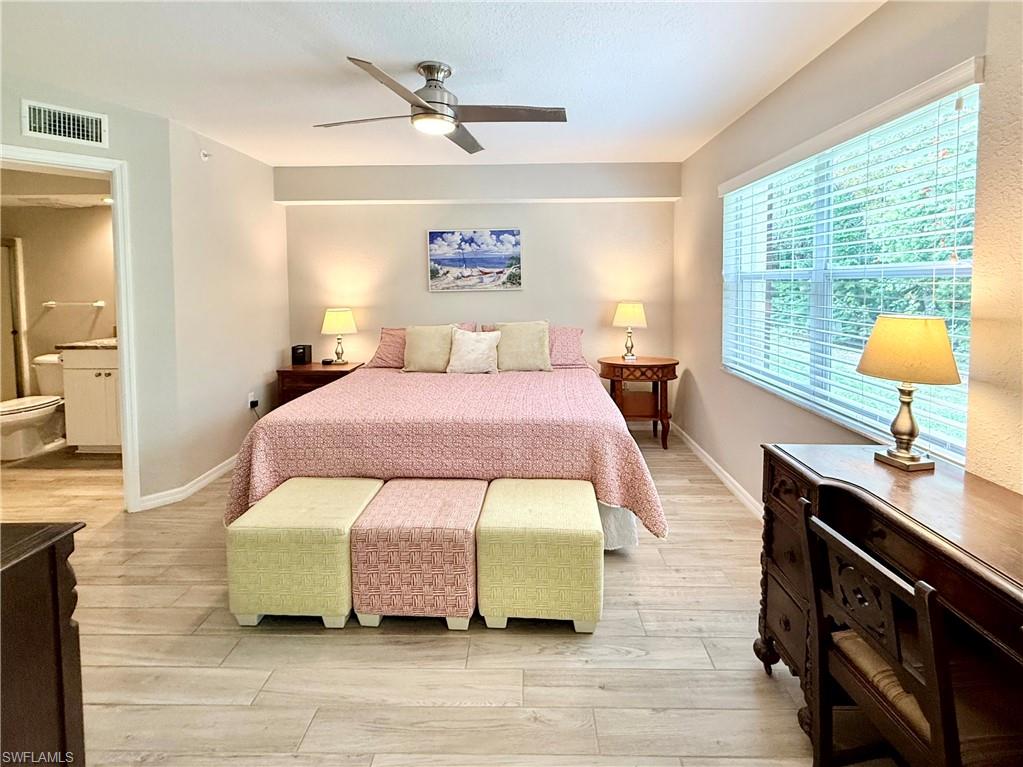 Bedroom featuring light wood-style floors, a ceiling fan, and ensuite bathroom