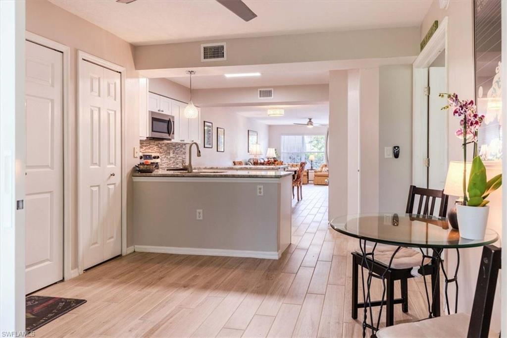 Kitchen with a ceiling fan, a peninsula, light wood finished floors, and white cabinetry