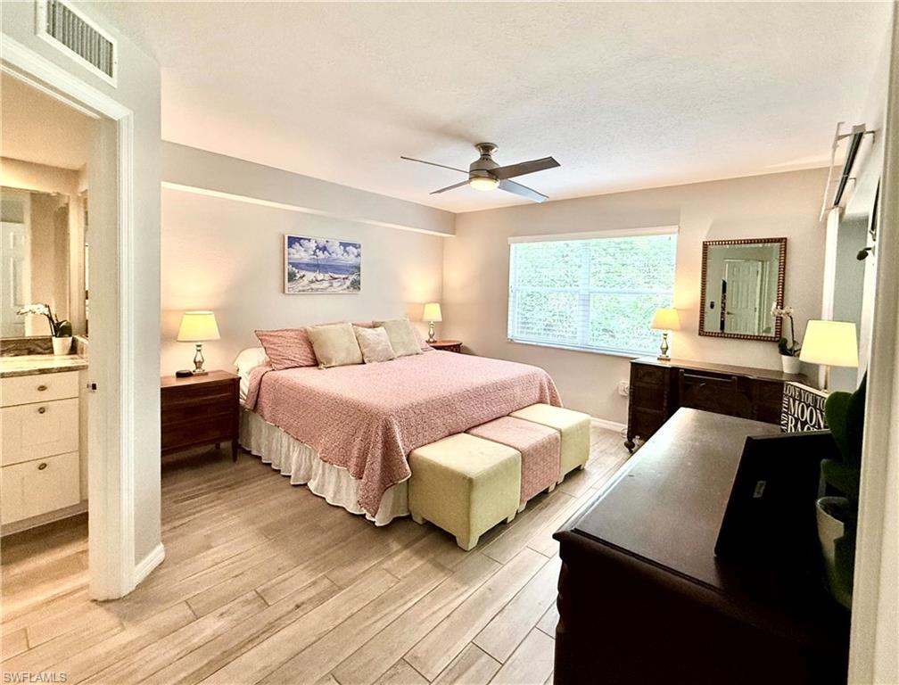 Bedroom with light wood-type flooring, ceiling fan, and a textured ceiling