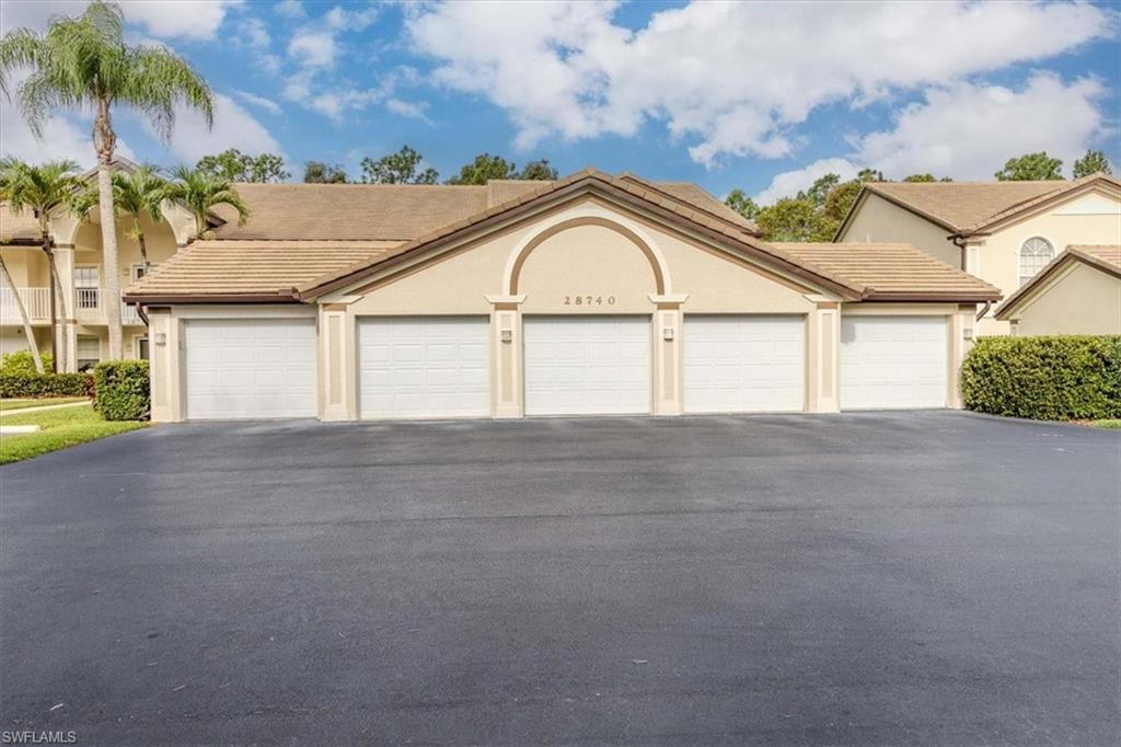 View of front of property with a tiled roof, community garages, and stucco siding