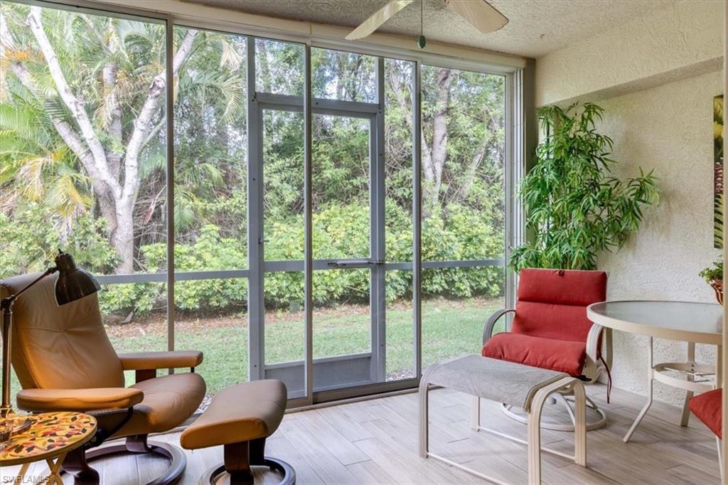 Sunroom featuring a textured wall, wood finished floors, a textured ceiling, and expansive windows