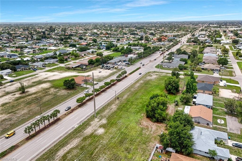 Expansive aerial showcasing a residential neighborhood with a prominent central roadway