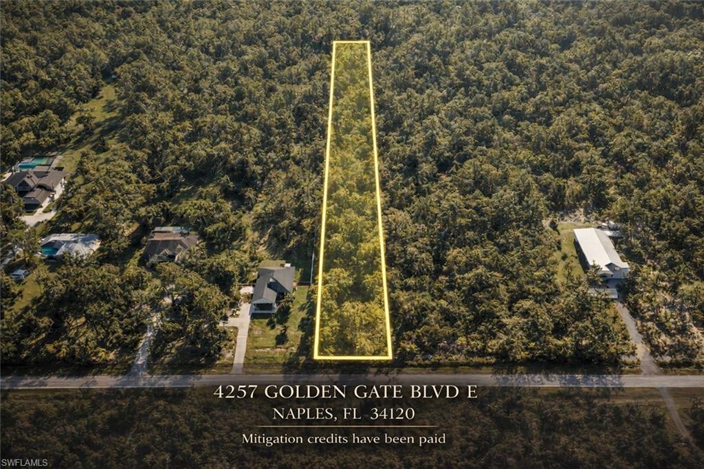 Aerial view of property and surrounding area with property parcel outlined and a heavily wooded area