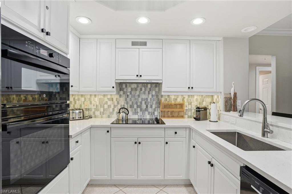 The kitchen features white cabinetry, a built-in oven, a black refrigerator, and a light-colored countertop