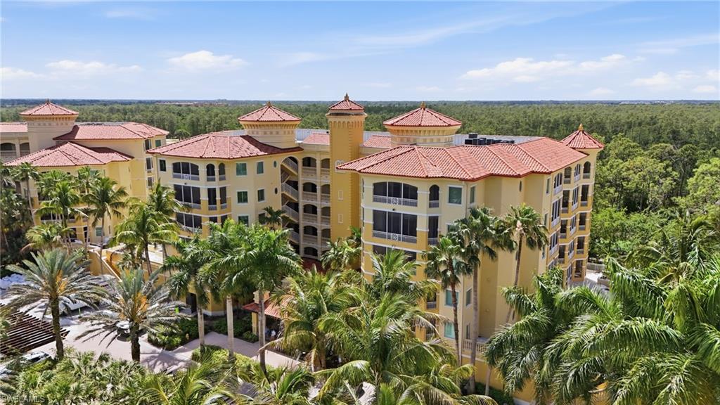 This property features a multi-story building with a light-colored facade and red tiled roofs