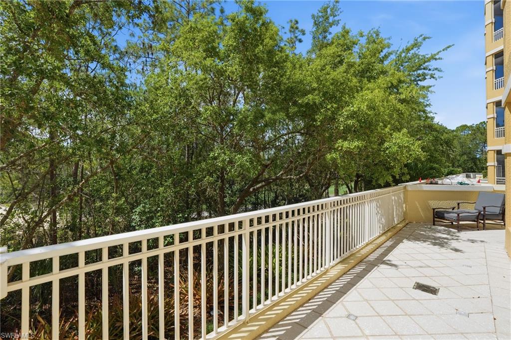 The property features an outdoor patio with a white railing and tiled flooring, providing tree-lined views
