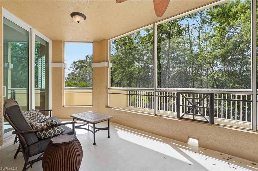 The property features a screened-in lanai with a textured ceiling, a ceiling fan, and views of lush greenery