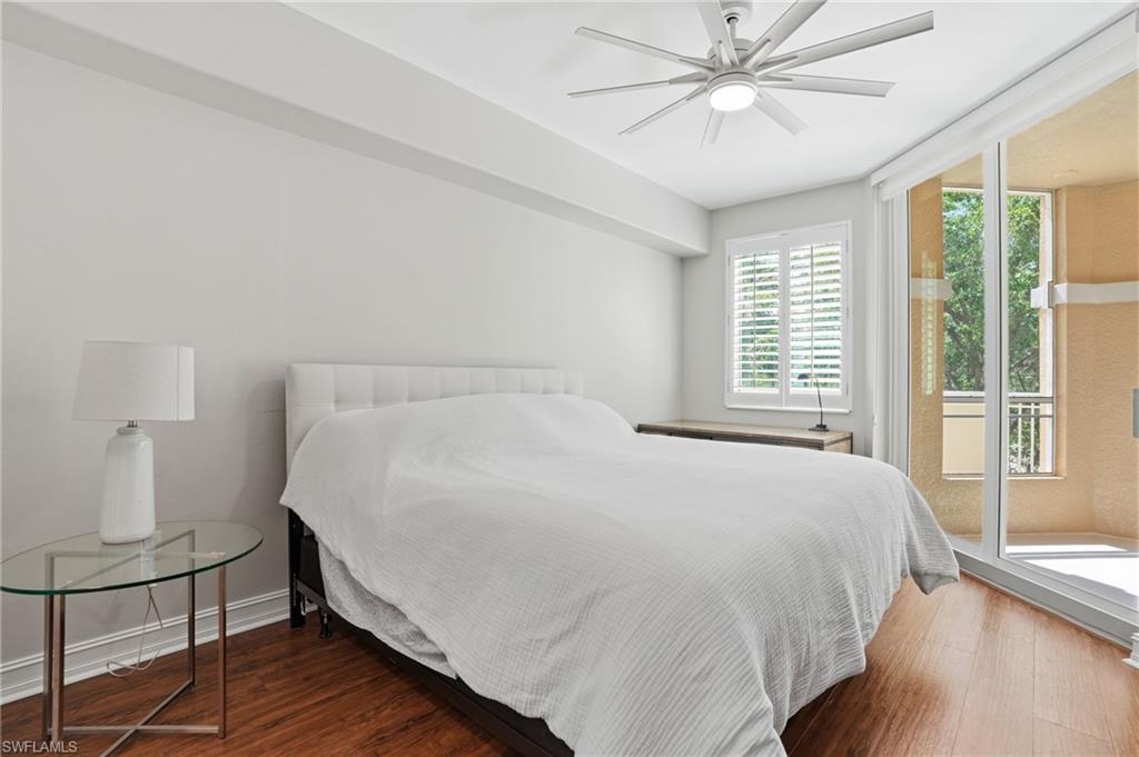 This room features hardwood flooring, a ceiling fan with light, and white walls
