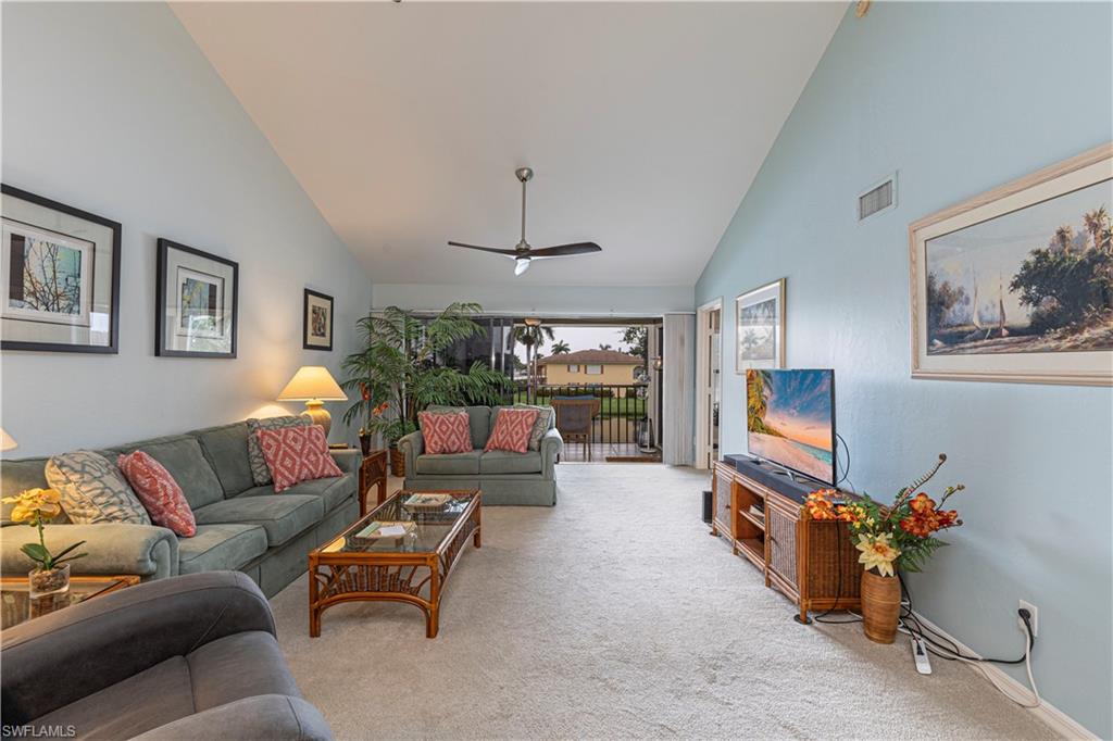 Carpeted living room featuring high vaulted ceiling and ceiling fan