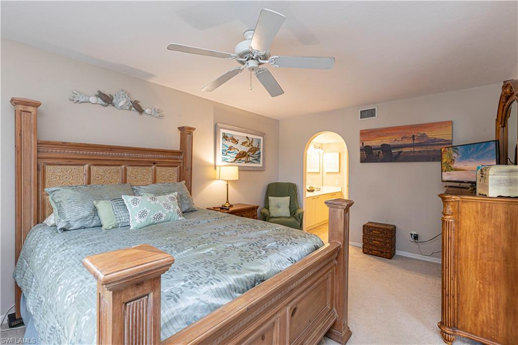 Carpeted bedroom with ensuite bathroom and ceiling fan