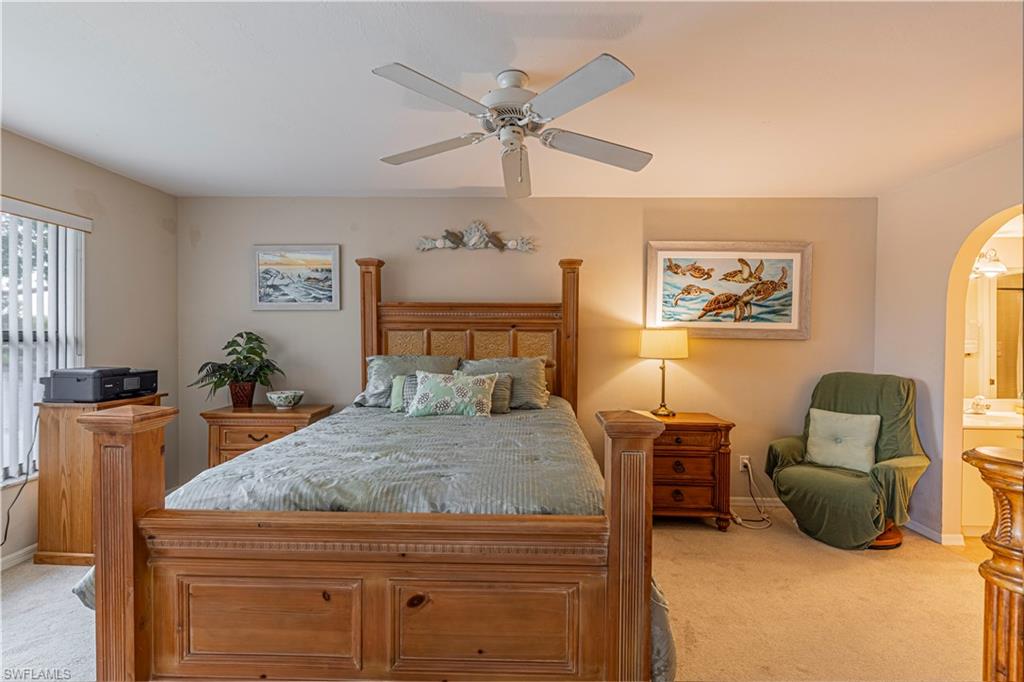 Carpeted bedroom with ensuite bath and ceiling fan