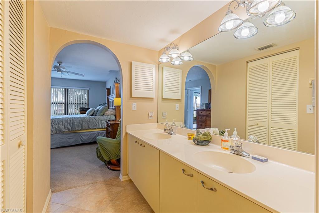 Bathroom with dual vanity, tile patterned flooring, and ceiling fan