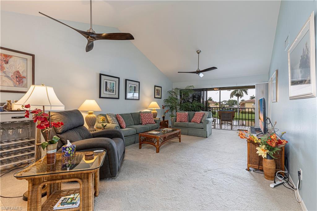 Carpeted living room with high vaulted ceiling and ceiling fan