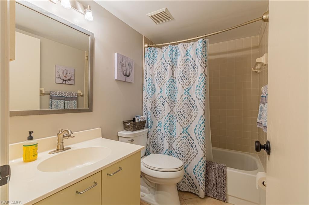 Full bathroom with vanity, shower / bath combo with shower curtain, tile patterned flooring, and toilet