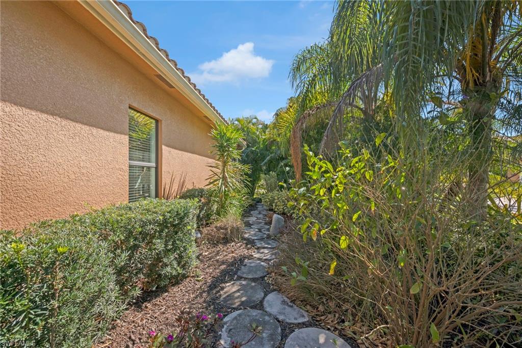 Private side walkway bordered by mature tropical landscaping and a decorative stone pathway.