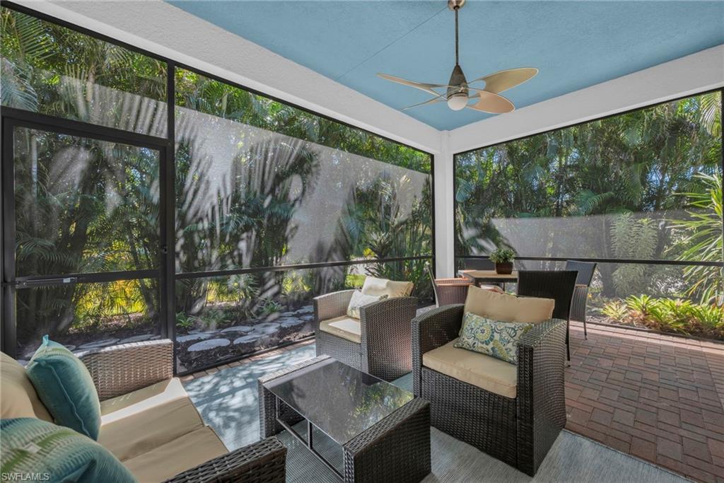 Screened lanai with ceiling fan and peaceful garden views, perfect for outdoor living.
