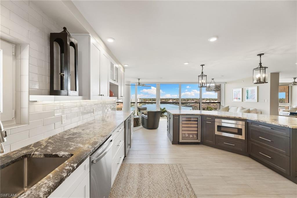 Kitchen featuring wine cooler, stainless steel dishwasher, white cabinetry, backsplash, and dark stone counters