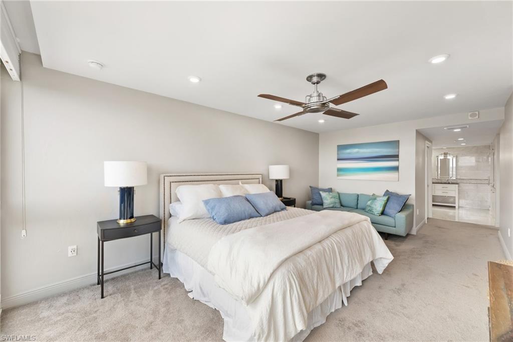 Bedroom featuring light colored carpet, recessed lighting, baseboards, a ceiling fan, and ensuite bath
