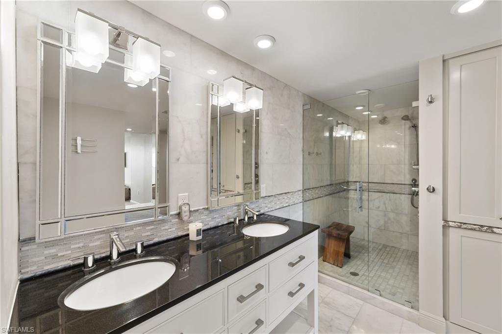 Full bath featuring a stall shower, double vanity, tasteful backsplash, and recessed lighting