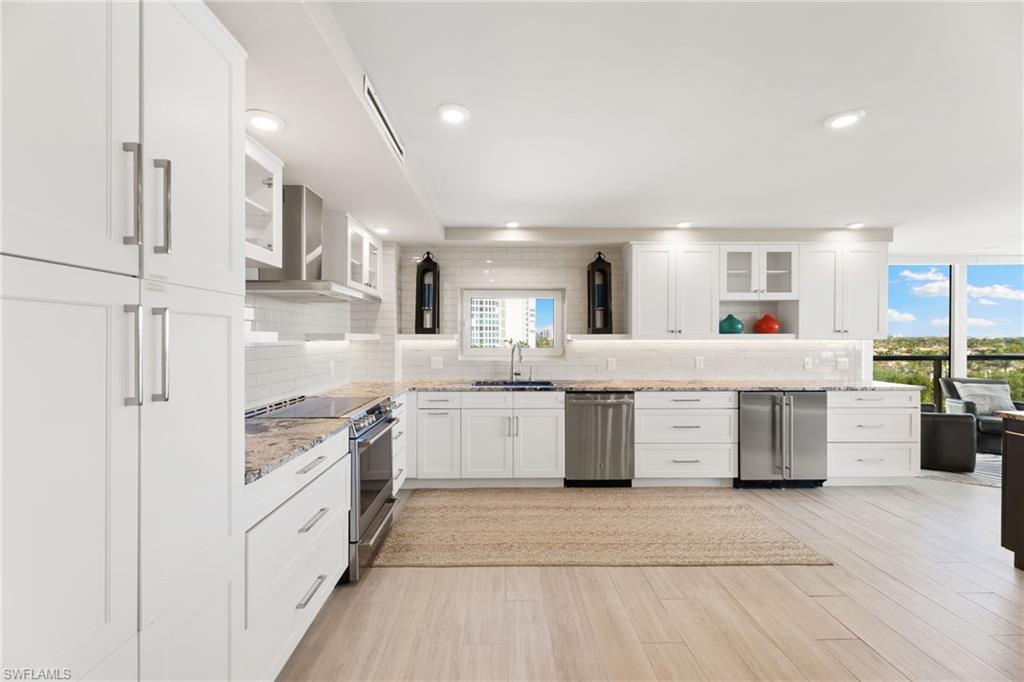 Kitchen featuring appliances with stainless steel finishes, tasteful backsplash, wall chimney exhaust hood, a sink, and recessed lighting