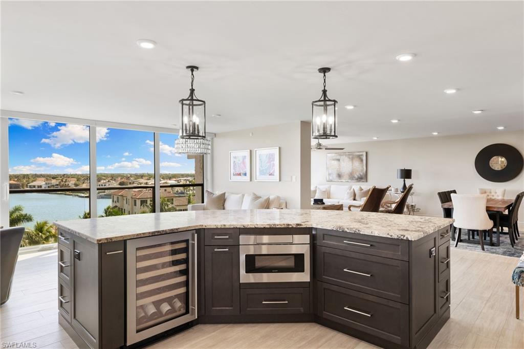 Kitchen featuring wine cooler, open floor plan, light wood-style floors, light stone countertops, and recessed lighting