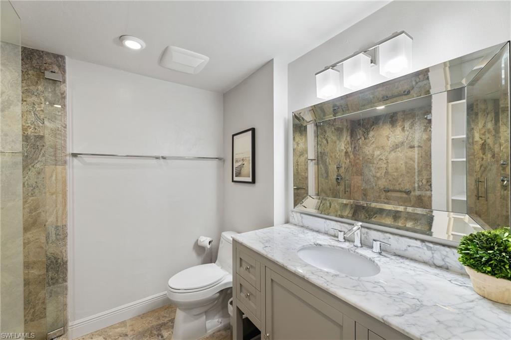 Full bath featuring a shower stall, vanity, toilet, and baseboards