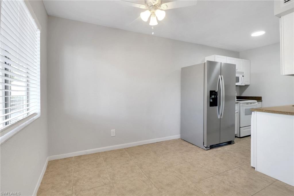 Kitchen featuring white appliances, white cabinets, a ceiling fan, and baseboards