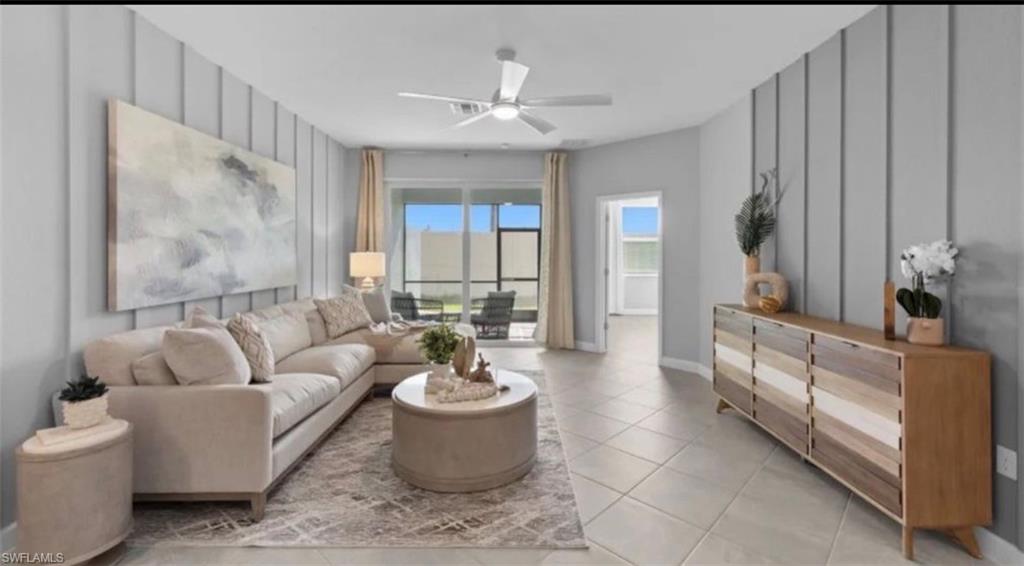 Living area featuring a ceiling fan, light tile patterned flooring, and a decorative wall