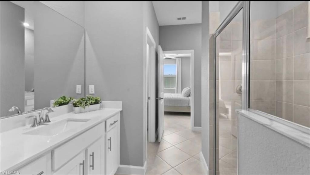 Full bath featuring a shower stall, connected bathroom, vanity, and light tile patterned floors