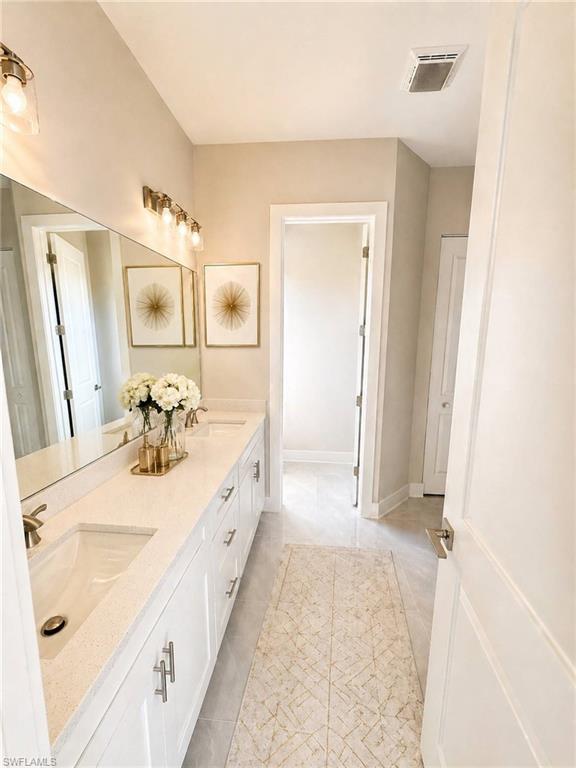 Double vanity featuring white shaker-style cabinetry, undermount sinks, and light-toned countertops