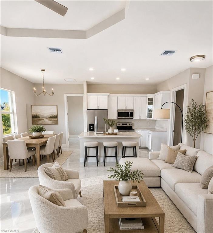 Open-concept living area with tray ceiling and recessed lighting