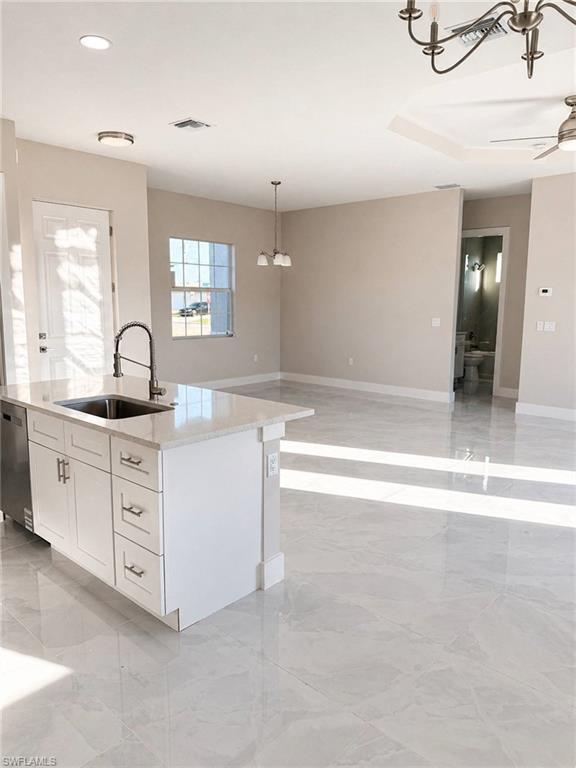 Contemporary kitchen island with white shaker cabinetry, quartz countertop, and a matte black faucet
