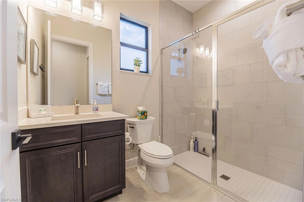Bathroom with tile patterned flooring, vanity, a shower with shower door, and toilet